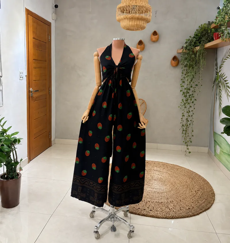 Black halter-neck wide-leg jumpsuit with strawberry print, front tie, waist cutouts and ornamental border hem.